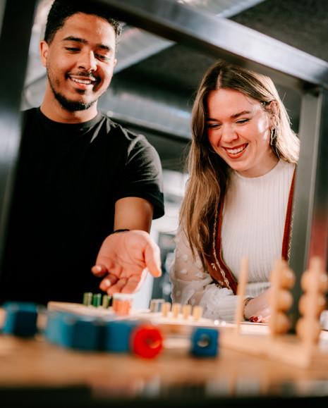 Twee bezoekers spelen mens-erger-je-niet op het doe-plein.