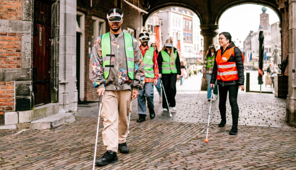 Bezoekers tijdens Expeditie ribbelroute samen met gids Melly die onder een boog doorlopen richting de Sint Stevenskerk in Nijmegen.