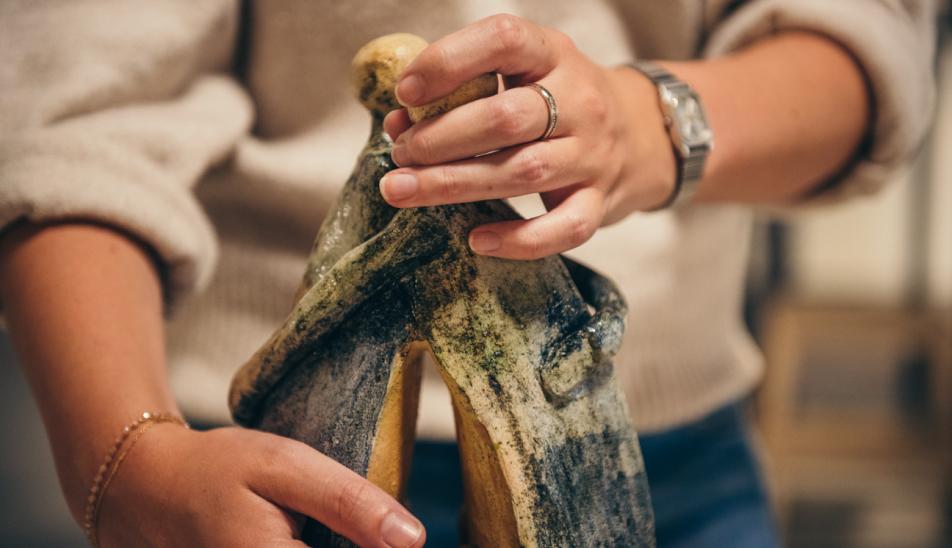 Expositie van Marleen de Man: een detailfoto van een bezoeker die met twee handen een beeld van Marleen de Man probeert te voelen.