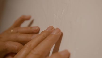 Een detailforo van twee handen die voelen aan een schilderij.